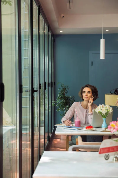 Nadenkend jonge vrouw huiswerk met laptop — Stockfoto