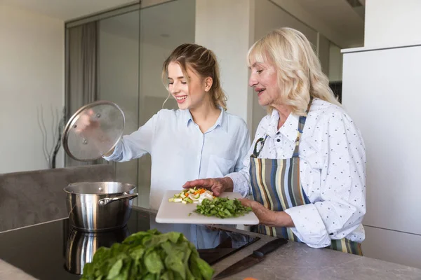 Feliz nieta y su abuela cocinando sopa de verduras — Foto de Stock