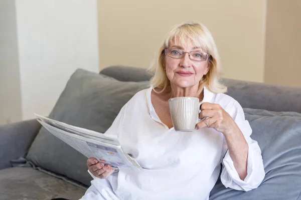 Старшая женщина в очках держит газету — стоковое фото