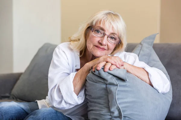 Милая пожилая женщина в очках, опирающаяся на подушку — стоковое фото