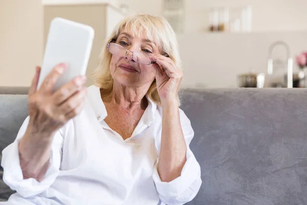 Красивая пожилая женщина в очках читает сообщение — стоковое фото