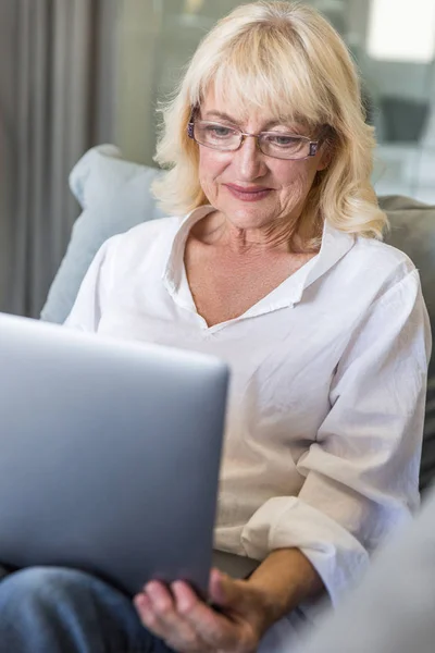 Mujer mayor en gafas graduadas usando computadora portátil — Foto de Stock