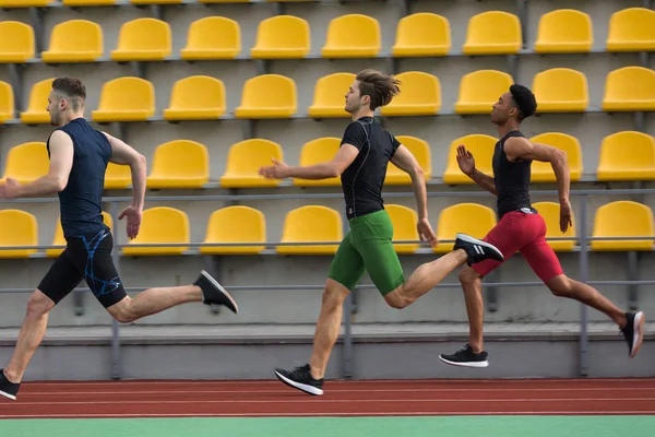 Un groupe d'athlètes multiethnique court en plein air sur une piste de course — Photo