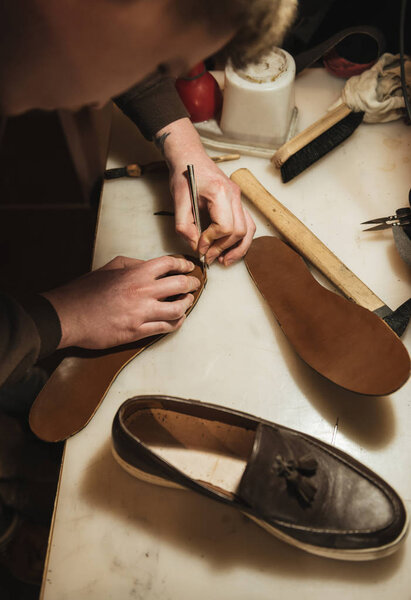 Cropped image of young concentrated man shoemaker