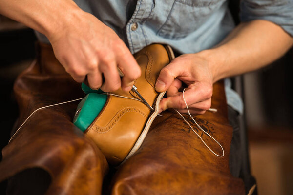 Shoemaker in workshop making shoes.