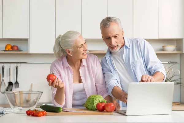 Familia feliz pareja amorosa madura usando el ordenador portátil y cocinar — Foto de Stock