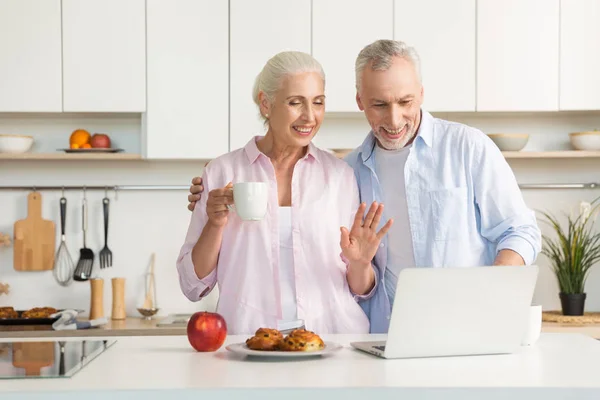 Sonriendo pareja amorosa madura familia comiendo pasteles mientras usa el ordenador portátil — Foto de Stock