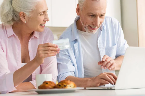 Szczęśliwy dojrzałe kochającą rodzinę pary za pomocą laptopa posiadania karty kredytowej — Zdjęcie stockowe