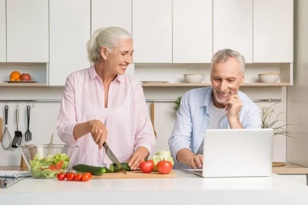 Zralé milující pár rodinu pomocí přenosného počítače a vaření salát — Stock fotografie