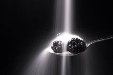 Siyah arka plan üzerinde izole böğürtlen kaşıkla.