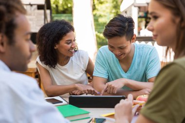 Neşeli genç çok ırklı arkadaşlar öğrenciler açık havada tablet kullanma