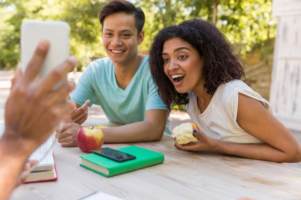 Förvånad multietniskt vänner titta på displayen av mobiltelefon. — Stockfoto