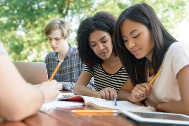 Çok ırklı grup oturma ve okuyan genç öğrenci