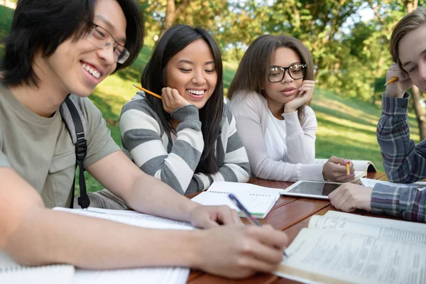 Estudantes sentados e estudando ao ar livre enquanto conversam — Fotografia de Stock