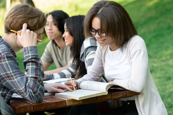 Jovens estudantes sentados e estudando ao ar livre enquanto conversam — Fotografia de Stock