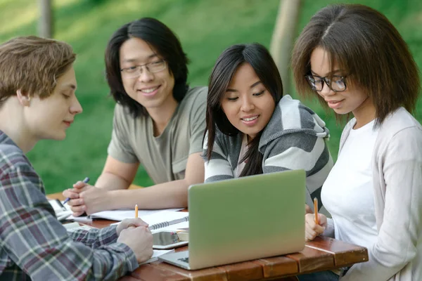 Fröhliche Gruppe junger Studenten, die sitzen und studieren — Stockfoto