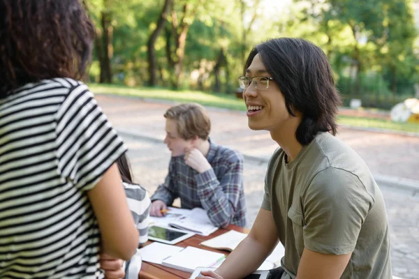 Lächelnde Gruppe junger Studenten, die sitzen und studieren — Stockfoto