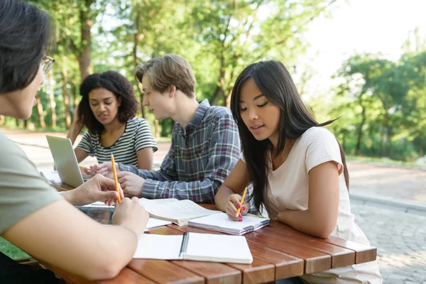 Grupo multiétnico de jovens estudantes sentados e a estudar — Fotografia de Stock