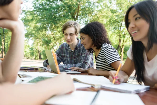 Young smiling students sitting and studying outdoors — Stock Photo, Image