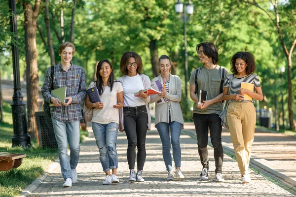Jóvenes estudiantes felices caminando mientras hablan. Mirando a un lado . — Foto de Stock