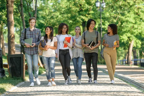 Jovens estudantes felizes andando enquanto conversam. Olhando de lado . — Fotografia de Stock