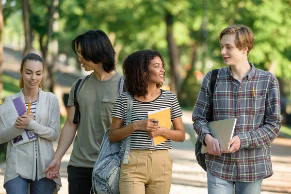Jovens estudantes felizes andando enquanto conversam. Olhando de lado . — Fotografia de Stock
