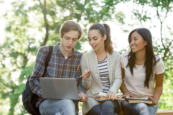 Grupo multiétnico de jovens estudantes sorrindo usando computador portátil — Fotografia de Stock
