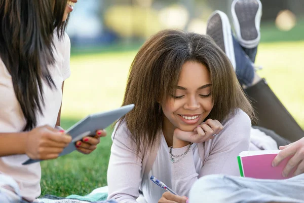 Lächelnde afrikanische Studentin, die im Freien studiert. Blick zur Seite. — Stockfoto