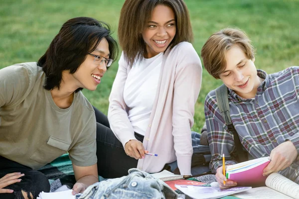 Lächelnde Studenten, die im Freien lernen. Blick zur Seite. — Stockfoto