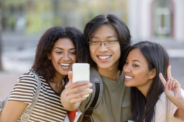 Estudiantes felices de pie y haciendo selfie al aire libre — Foto de Stock