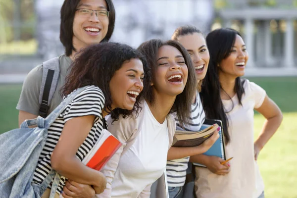 Multi-etnische groep van jonge gelukkig studenten permanent buitenshuis. — Stockfoto