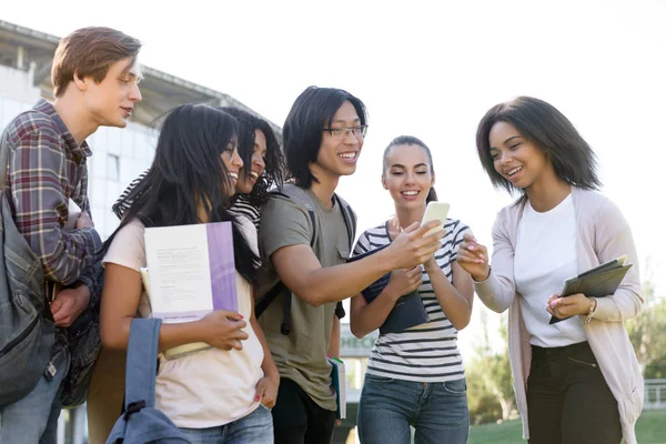 Grupo multiétnico de jóvenes estudiantes felices usando el teléfono móvil — Foto de Stock