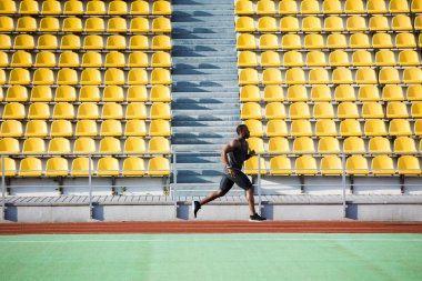 Yarış pisti üzerinde çalışan bir sporcu tam uzunlukta yan görünüm