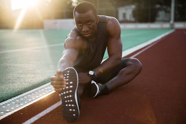 Deportivo muscular africano atleta masculino estirar las piernas — Foto de Stock