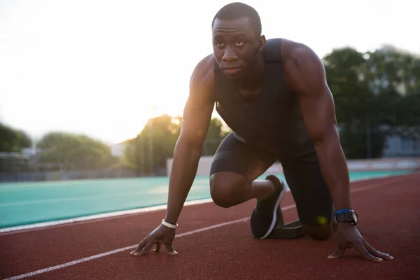 Joven atleta africano a punto de comenzar una carrera de sprint — Foto de Stock