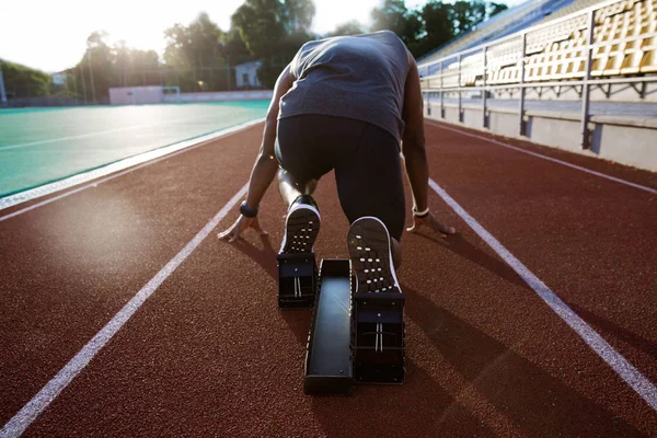 Vista posterior de un joven atleta masculino en el bloque de inicio — Foto de Stock