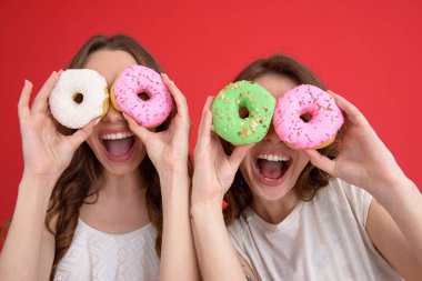 Çörek ile ayakta gülümseyen iki bayan arkadaş