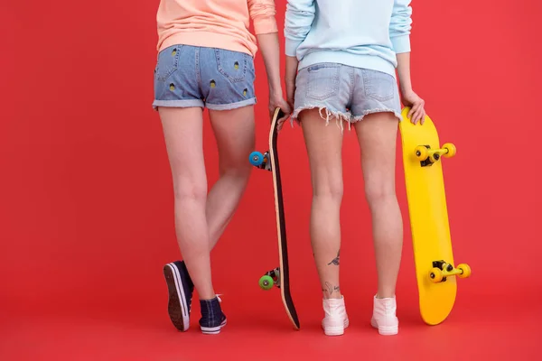 Imagen recortada de dos señoras jóvenes sosteniendo patinetas . — Foto de Stock