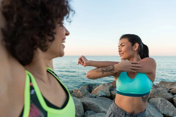 Two happy young sportswomen stretching hands — Stock Photo, Image