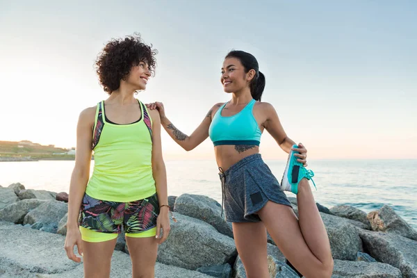 Two young sportswomen stretching at the beach — Stock Photo, Image