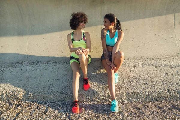 Två unga fitness kvinnor i sportkläder talar — Stockfoto