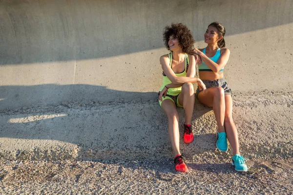 Två glada sportiga kvinnor i sportkläder sitter tillsammans — Stockfoto