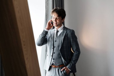 İşadamı duran ve kapalı cep telefonu üzerinde konuşurken elbiseli