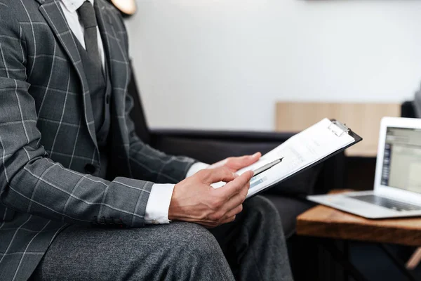 Cropped image of a man in suit analyzing documents