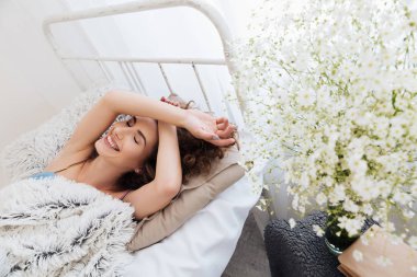 Genç kadın kapalı yatakta yatıyor. Bir kenara arıyorsunuz.