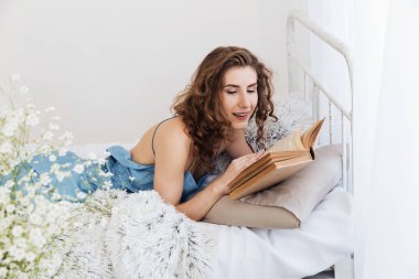 Güzel genç kadın kapalı kitap okuma yatakta yatıyor