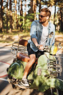 Açık havada scooter üzerinde oturan adam konsantre genç sakallı