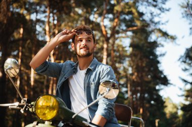 Açık havada scooter üzerinde oturan adam ciddi genç sakallı