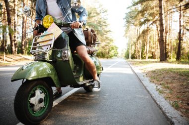 Genç adam açık havada scooter üzerinde.