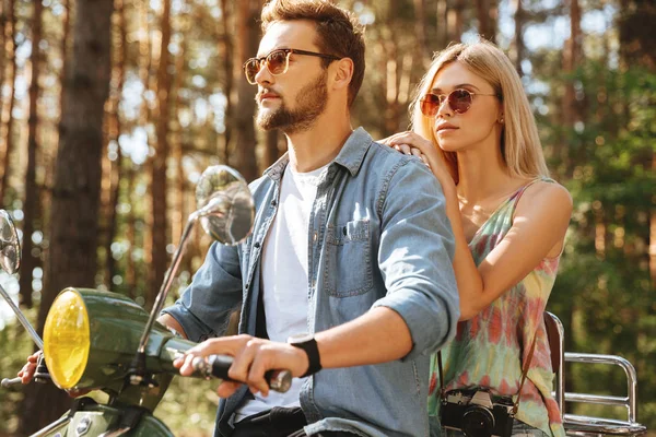 Bearded man on scooter with girlfriend outdoors